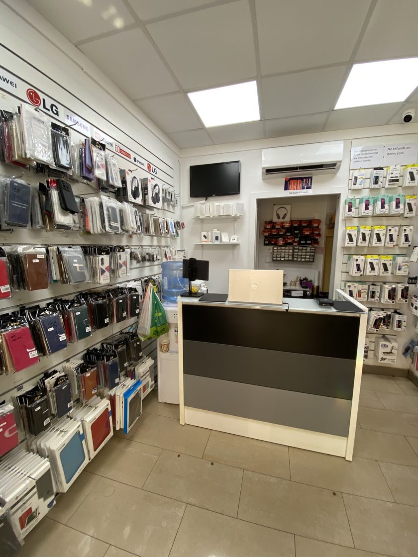 The inside of the shop, with the case wall on the left under a strip of brand logos, the service counter in the middle and screen protectors on the right hand wall