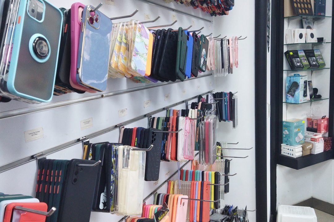 The phone case wall at Malta Tech, rows of cases in every colour hung on labelled hooks from floor to ceiling